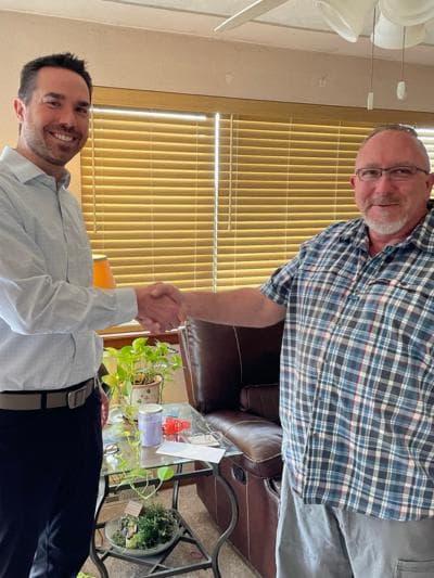 Brendan McQuaid shaking hands with a client in a plaid shirt, in a living room